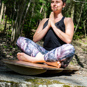 Jóga balanční prkno Funboards s krásnou jogínkou v sedu s rukama v modlitbě